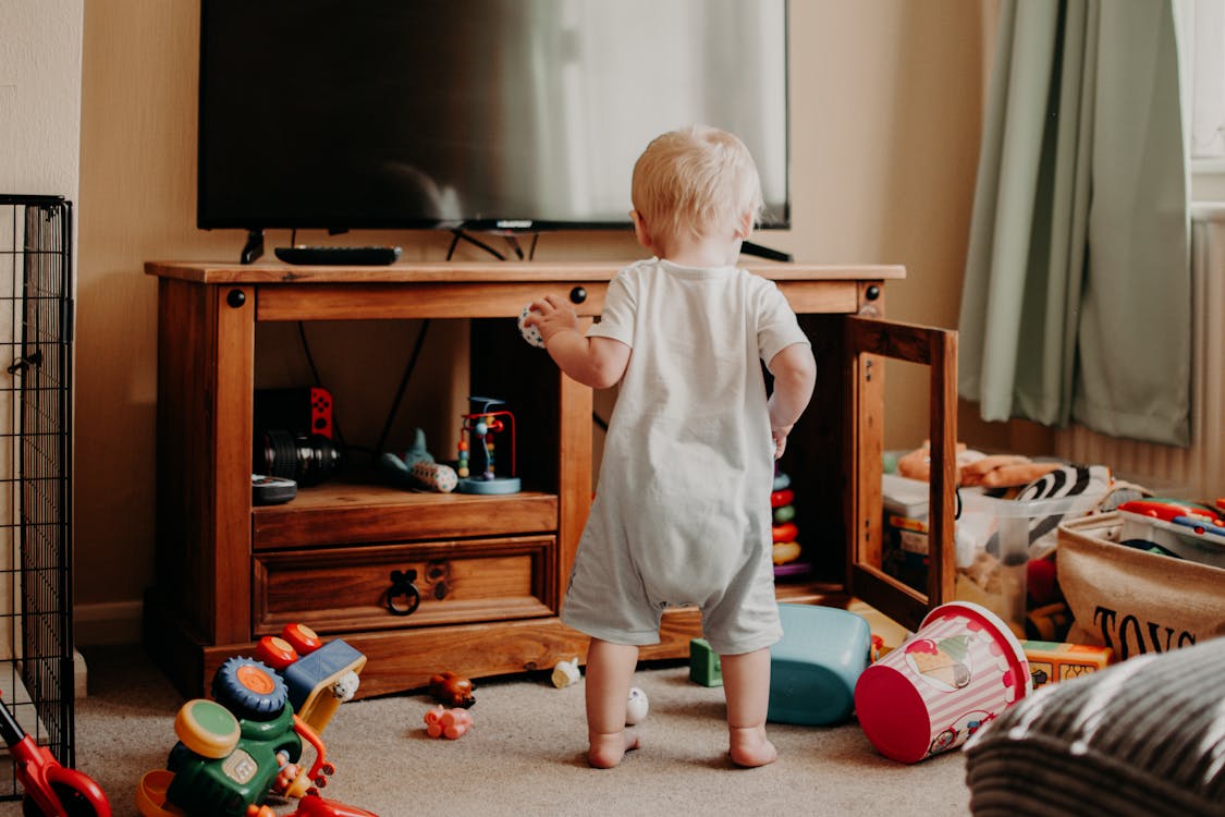 Toddler playing around clutter of toys