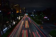 夜晚，繁忙的城市街道上，充满活力的灯光路径和高耸的摩天大楼长时间地展示着