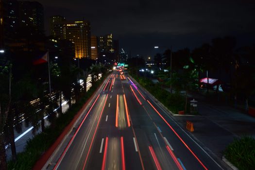 夜晚，繁忙的城市街道上，充满活力的灯光路径和高耸的摩天大楼长时间地展示着