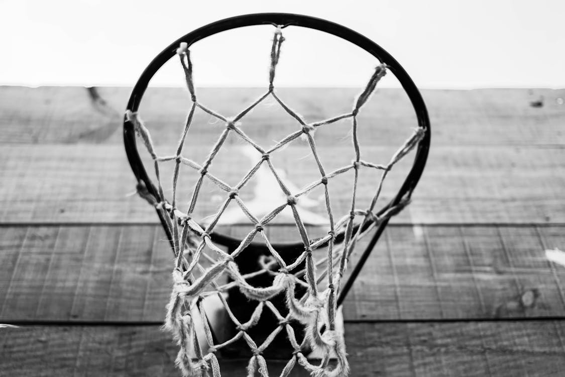 Free Low angle of black and white basketball mesh net and hoop hanging on wooden backboard on sports ground Stock Photo
