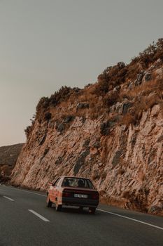 A vintage car travels on a winding mountain road, showcasing a breathtaking landscape.