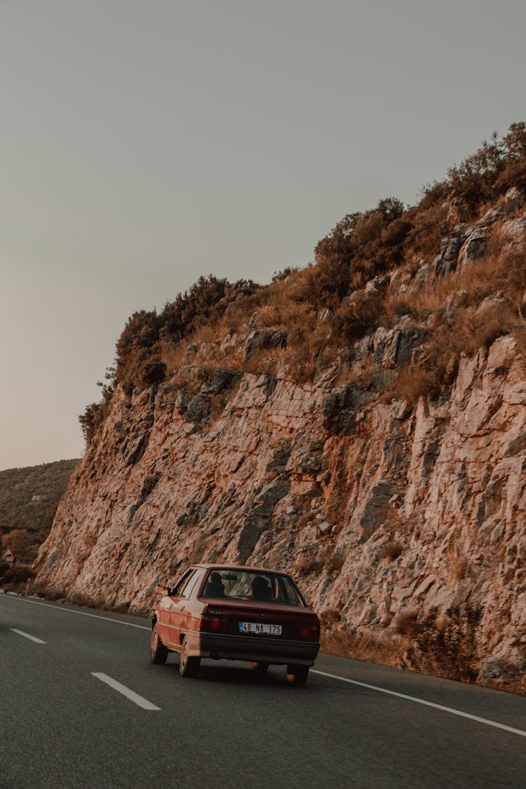 Red Classic Car On Road Near Brown Rock Mountain