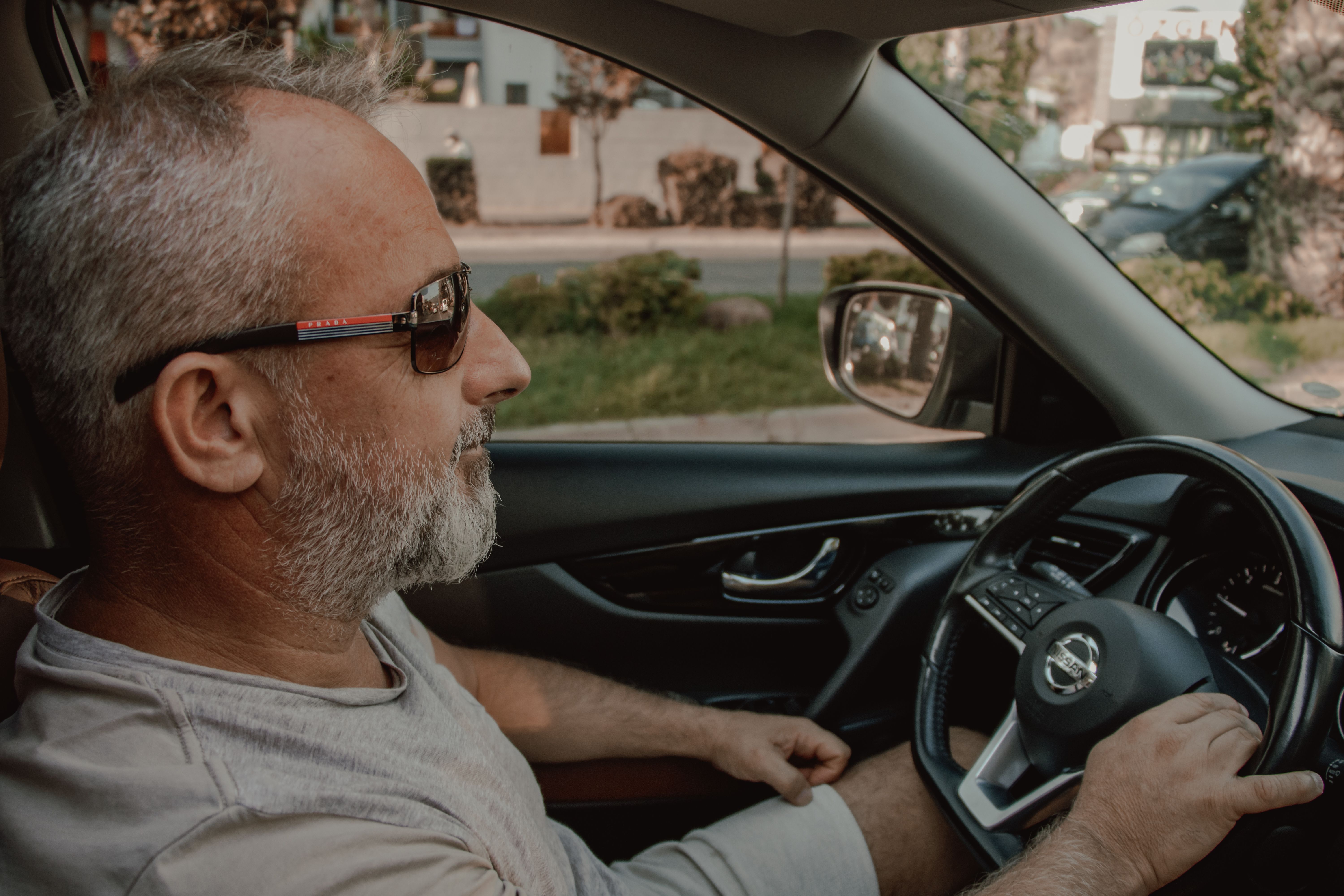 Man in grey shit driving a car