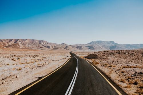 Free Captivating view of an empty road through the arid Negev desert landscape under a clear sky. Stock Photo