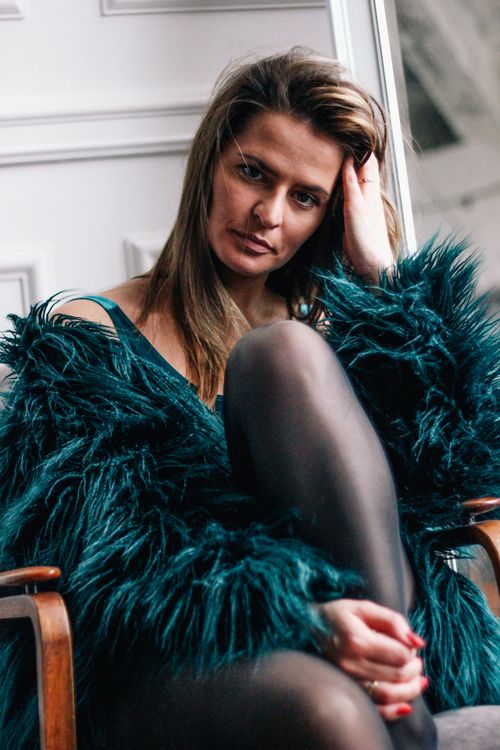 Free Elegant woman wearing a blue fur coat while sitting indoors, showcasing a serious and contemplative look. Stock Photo