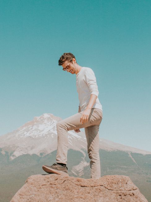 Man standing on rock with scenic view of Mount Hood under clear blue sky in Oregon.