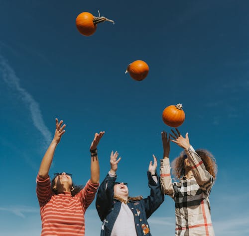 People Holding Orange Basketball Under Blue Sky