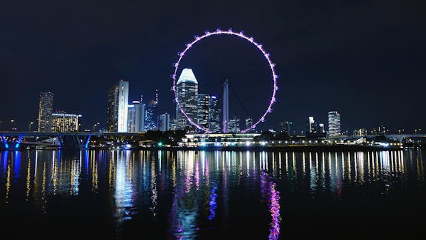 新加坡摩天观景台在夜间倒影滨海湾，映衬着新加坡天际线的景色
