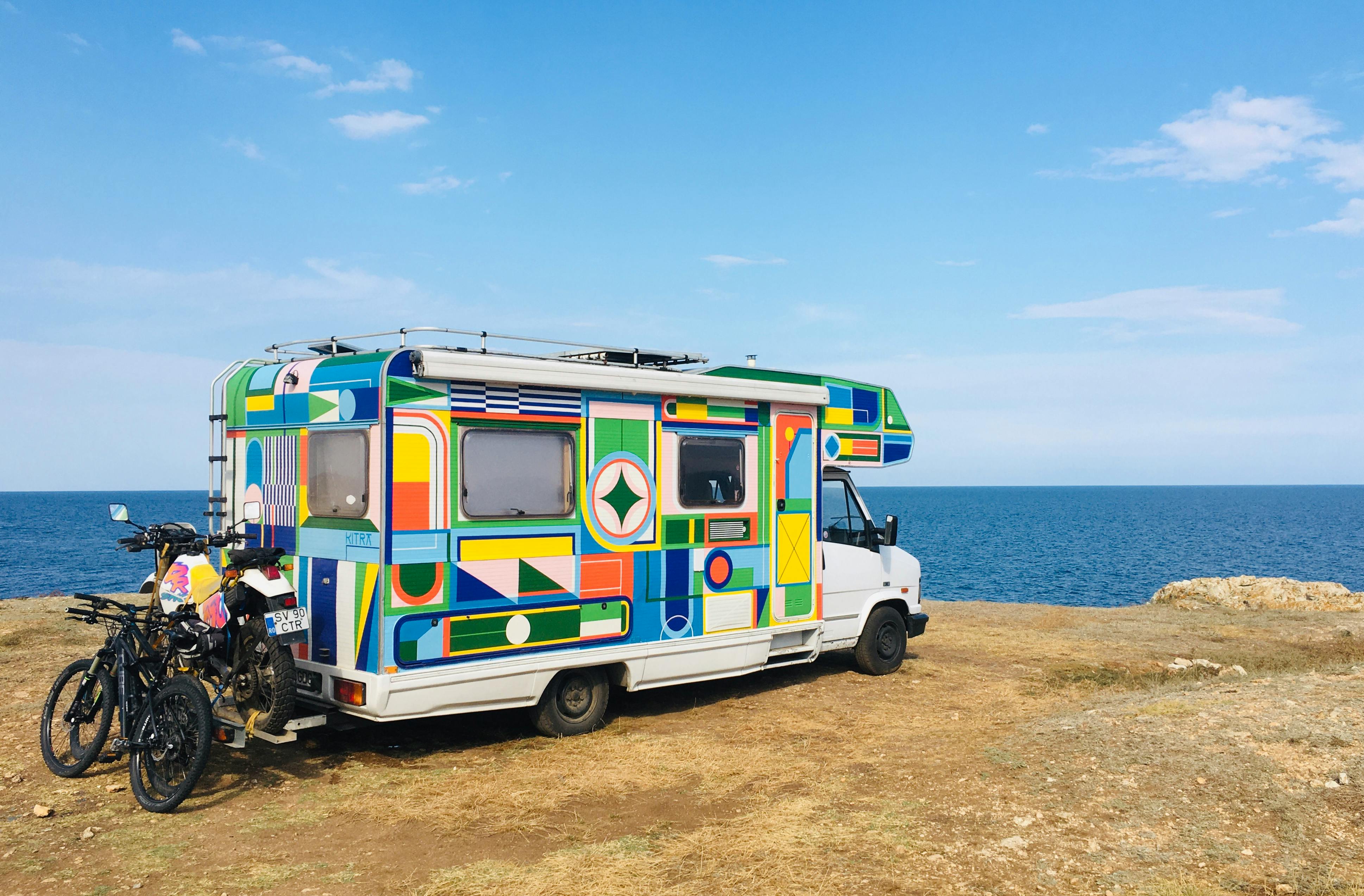 Man using a wrench to fix a small ATV outdoors during sunset.