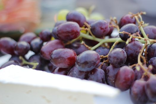 Close-up shot of fresh red grapes and cheese showcasing natural abundance and vibrant colors.