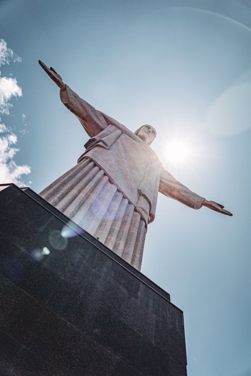 Free Iconic Christ the Redeemer statue in Rio de Janeiro captured from a low angle against the sun. Stock Photo