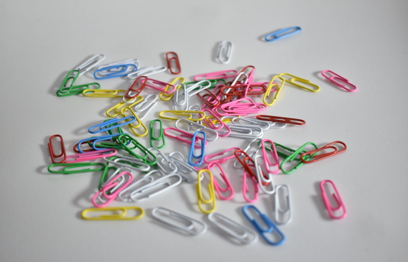 Vibrant multicolor paperclips scattered, offering a splash of color against a neutral background.