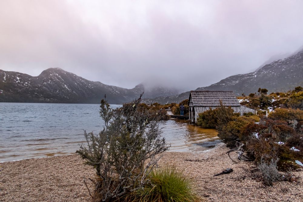 Cobertizo de madera junto a Dove Lake envuelto en niebla con montañas al fondo