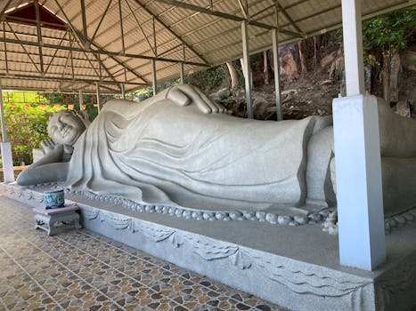 A large stone Buddha statue lies peacefully in a temple setting, showcasing spirituality and tranquility.