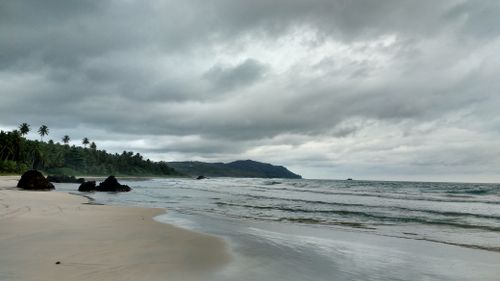 Free Tranquil beach scene with cloudy sky and palm-lined shore in North Sumatra, perfect for travel inspiration. Stock Photo