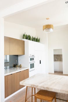 Bright minimalist kitchen interior featuring marble countertops and a chandelier.