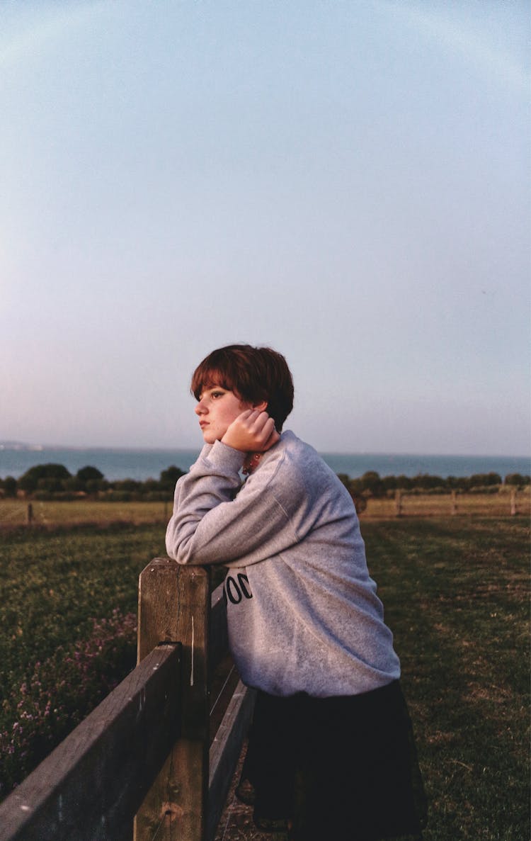 Woman Leaning Her Elbow On Brown Wooden Fence