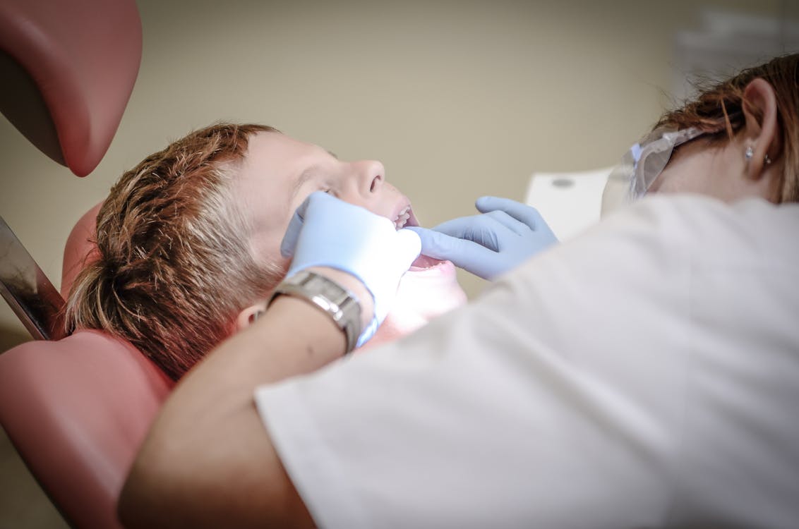 Mujer Dentista Vestida Con Guantes Blancos Y Traje Blanco Comprobando Los Dientes Del Niño