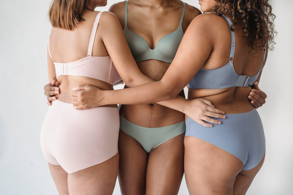 Two young women embracing their natural bodies while wearing brown  underwear stock photo
