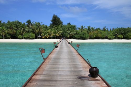 Free Stunning wooden pier leading to a tropical paradise with turquoise waters and lush palms in the Maldives. Stock Photo