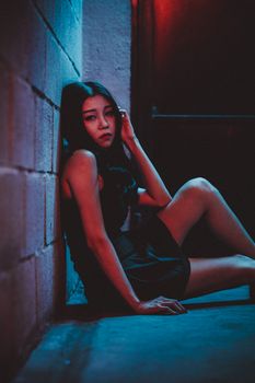 灯光昏暗，一名年轻女子若有所思地坐在砖墙上