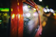 Vehicle with wet glass on night street with glowing lights