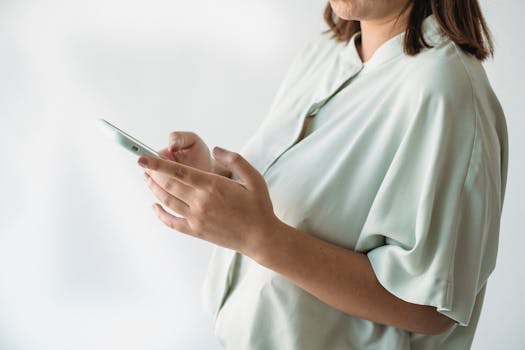 A woman in a light shirt using a smartphone indoors, focus on technology interaction.