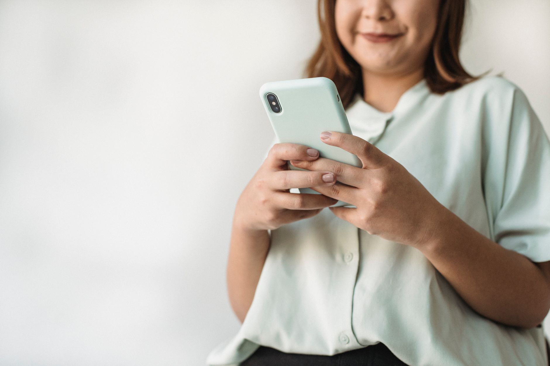 Close-up of a woman using a smartphone indoors with ample copy space.