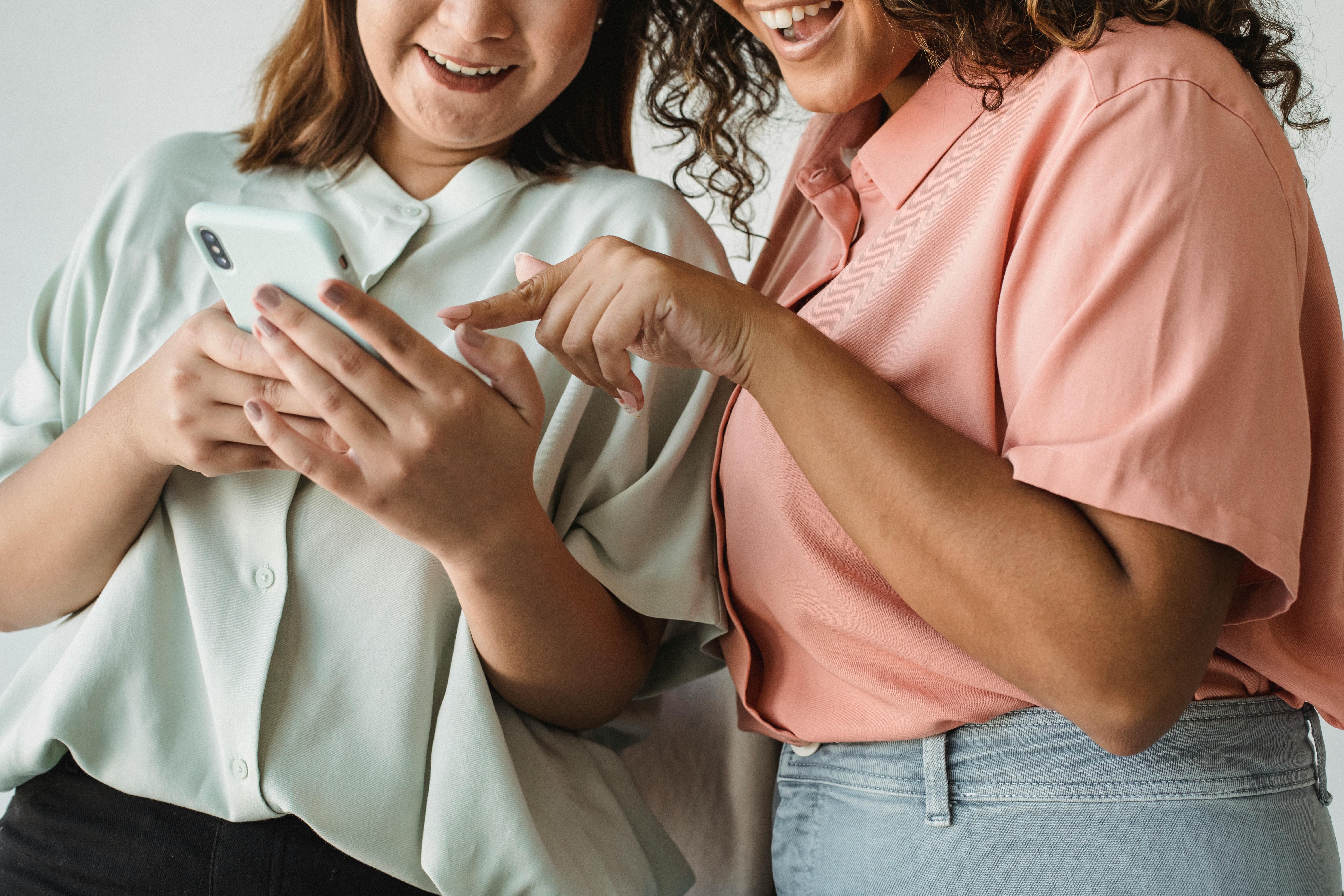 Close-up of two women interacting with a smartphone, smiling and engaging with technology.