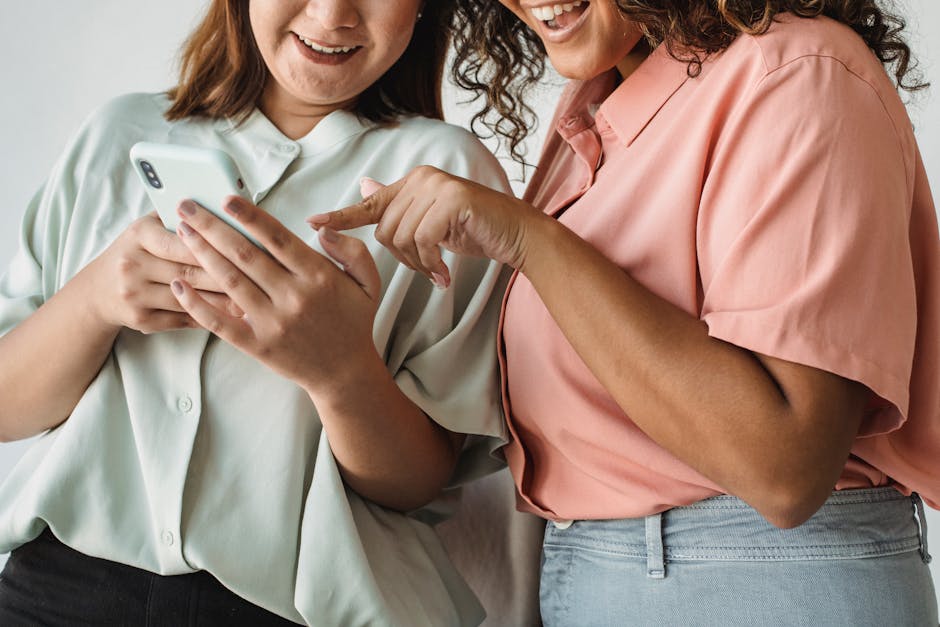 Noom vs WeightWatchers: Behavioral Tracking for Weight Loss (2026) Close-up of two women interacting with a smartphone, smiling and engaging with technology.