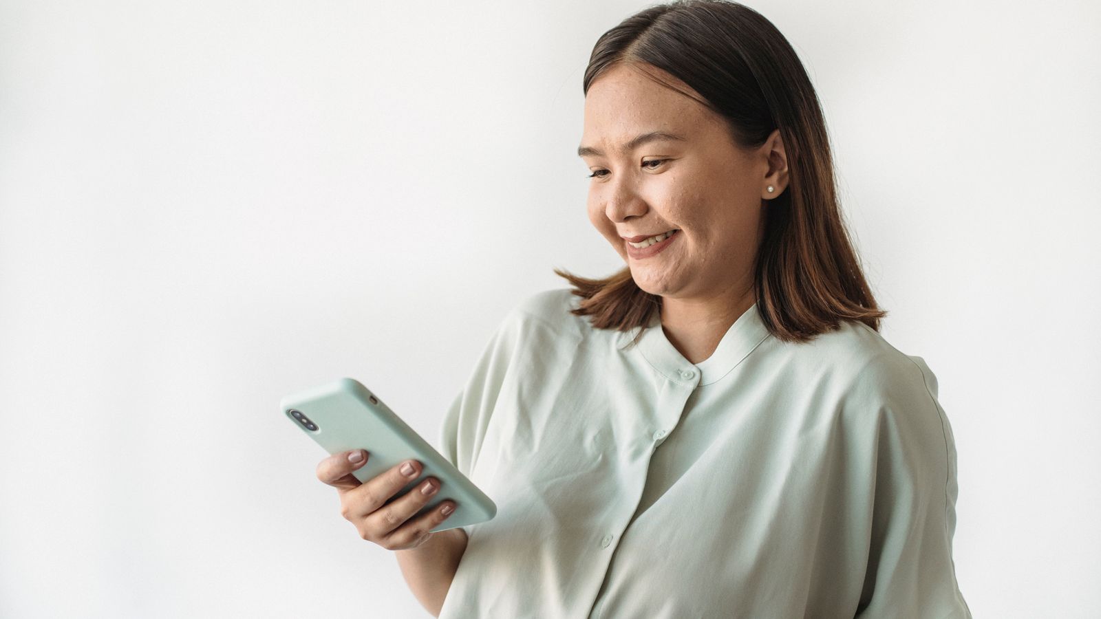 A woman smiling while reading a message on her smartphone