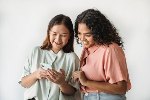 Women Smiling while Looking at the Smartphone