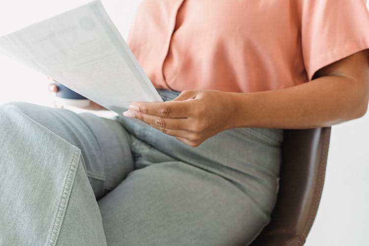 Close-up Of Woman Sitting In Chair Reading Document