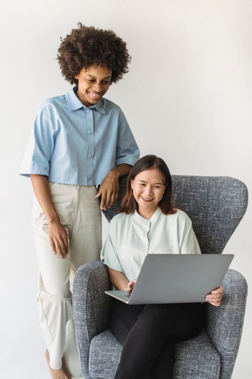 Free Two women collaborating on a laptop while smiling. Perfect for business or teamwork concepts. Stock Photo