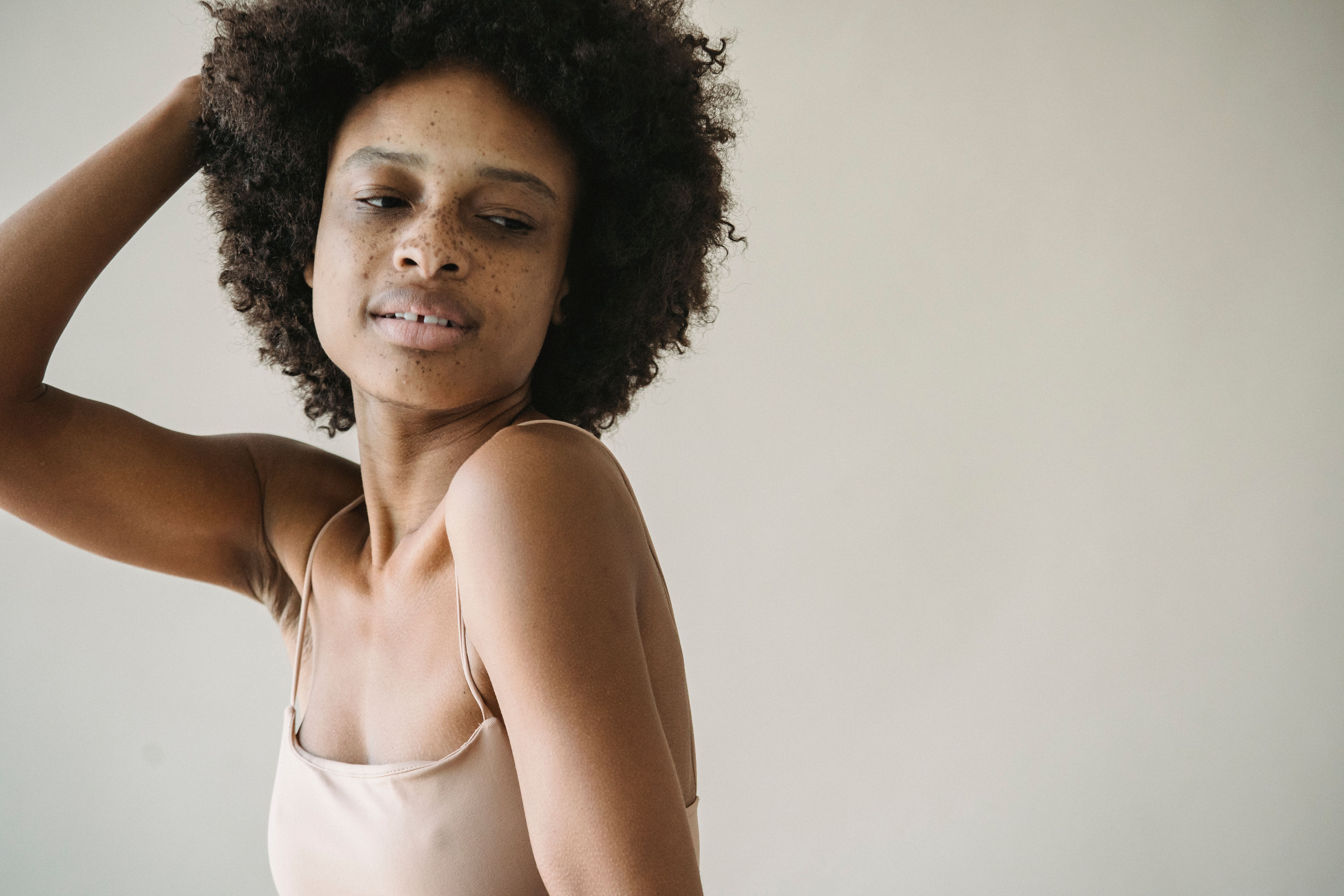 Artistic portrait of a woman with curly hair and natural freckles posing gracefully.