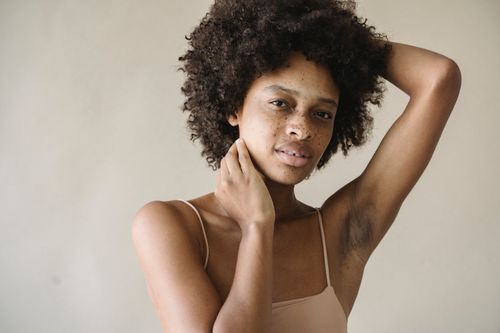 Free Close-up of a woman with afro hair and freckles posing thoughtfully in a studio setting. Stock Photo