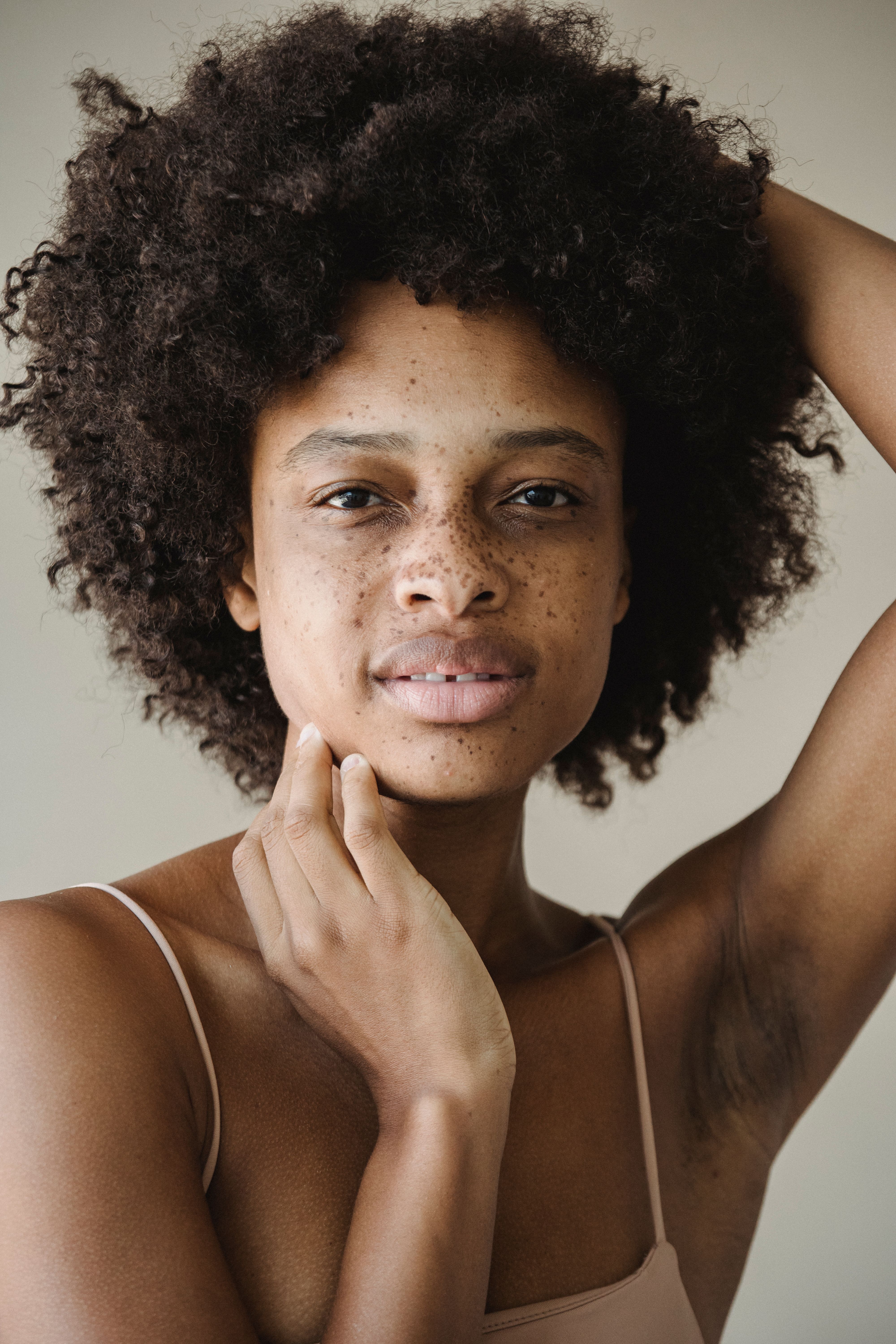 Close-up portrait of a woman with afro hair and freckles, showcasing natural beauty and confidence.