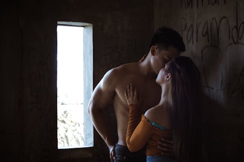 Anonymous couple kissing in shabby house