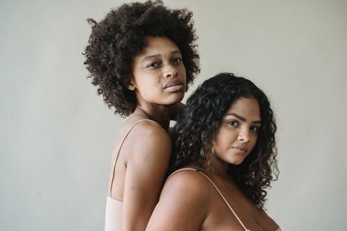 Free Portrait of two women embracing natural afro and curly hairstyles, highlighting diversity and beauty. Stock Photo