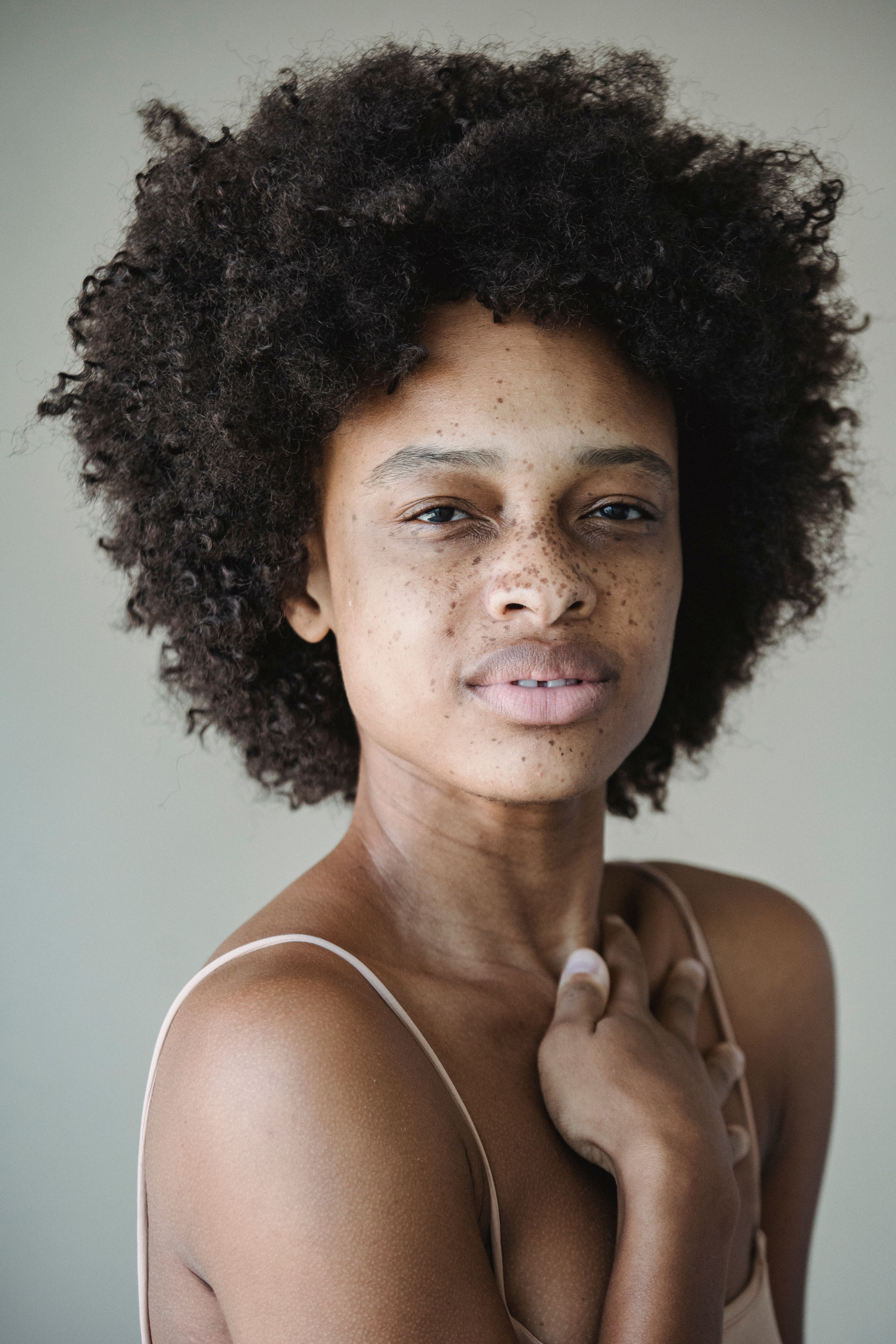 Close-up portrait of a woman with natural hair and freckles, a gentle expression.