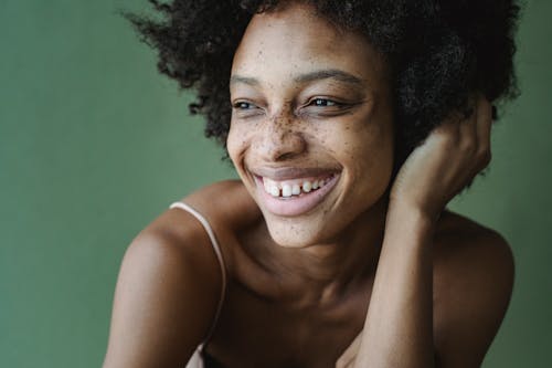Portrait of Woman with Afro Hairstyle and Freckles against Green Background