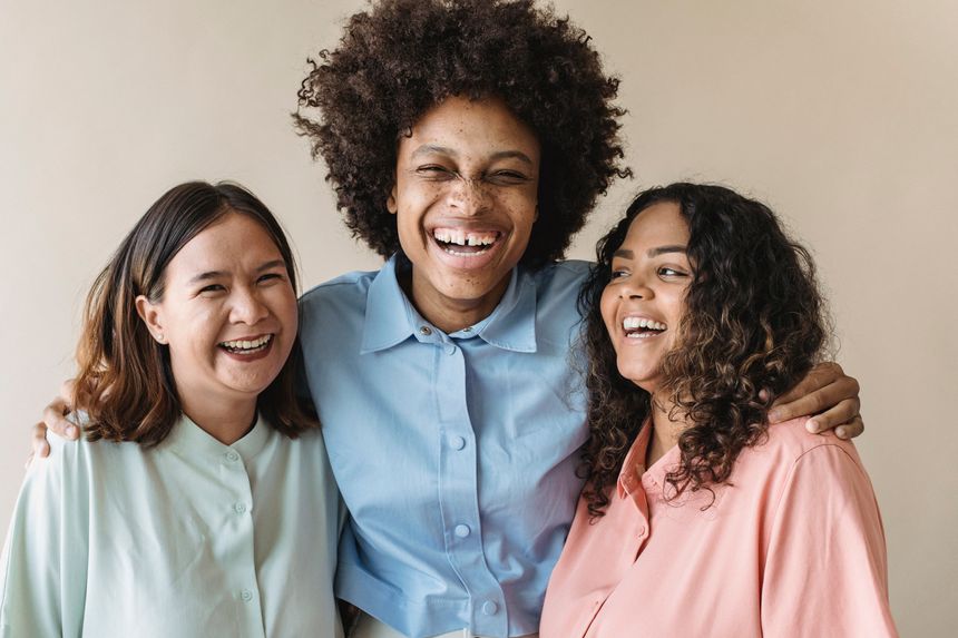 Three friends sharing a joyful moment — photo by Antonius Ferret on Pexels