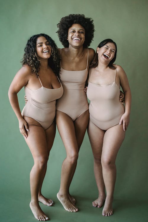 Women in Bodysuits Standing Together and Smiling