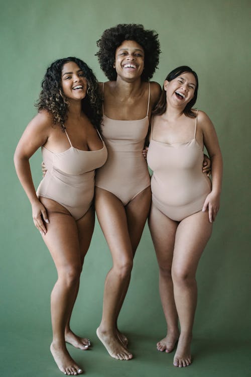 Women in Bodysuits Standing Together and Smiling 