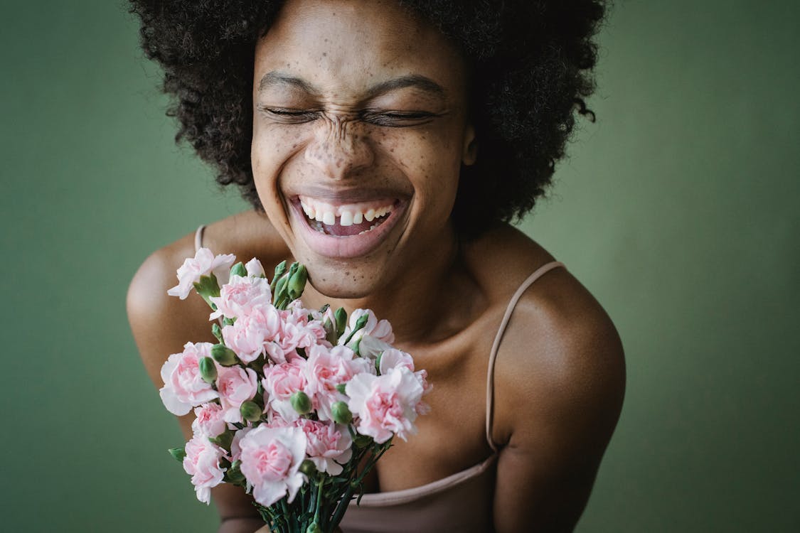 Woman Smiling and Holding a Bunch of Flowers 