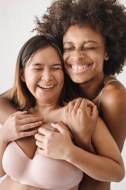 Two women hugging and smiling with eyes closed, portraying joy and friendship.