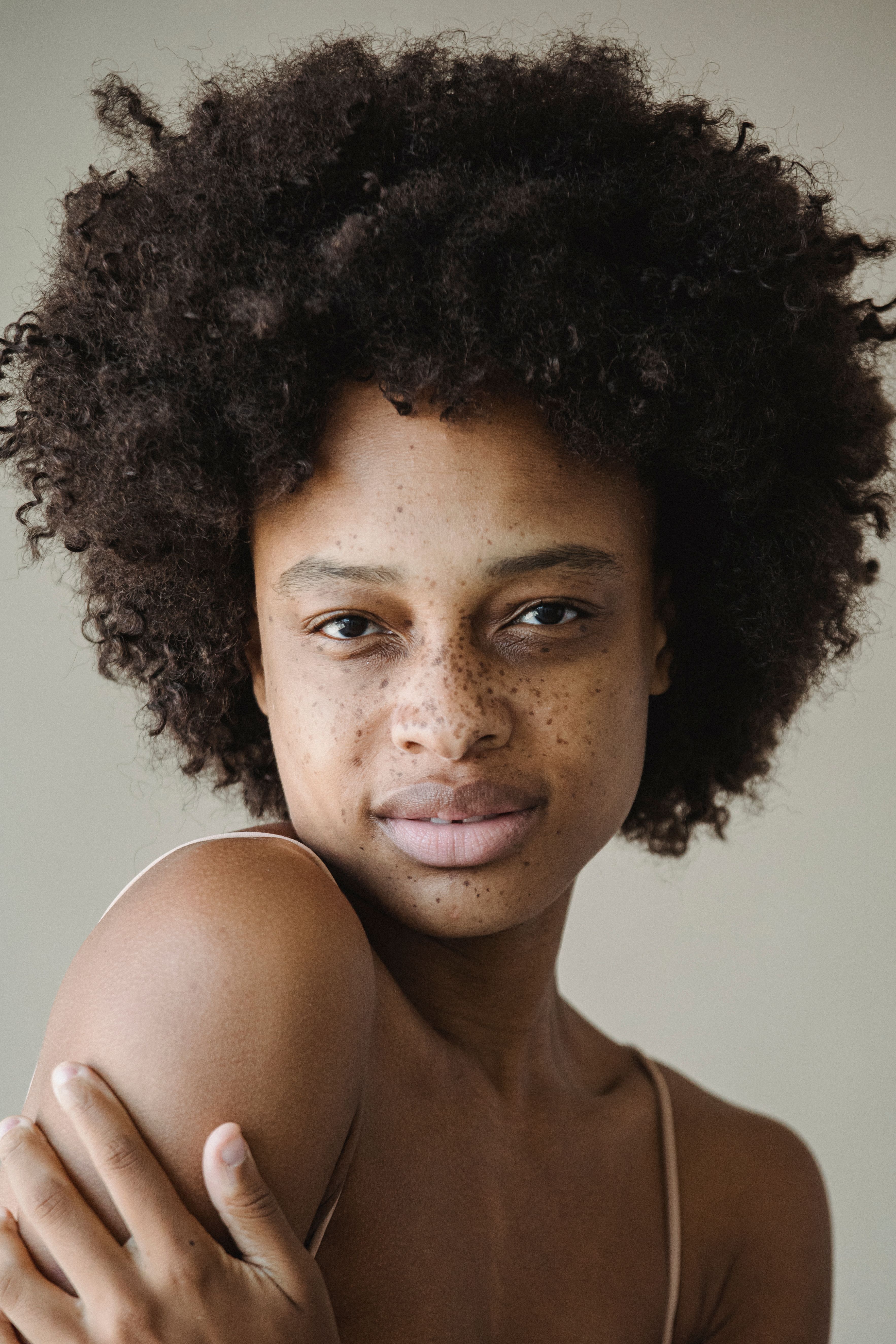 Close-up portrait of a freckled woman embracing natural beauty with afro hairstyle.