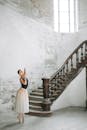 一位优雅的芭蕾舞演员在优雅的室内环境中摆姿势，带有复古楼梯