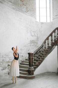 一位芭蕾舞演员在带有复古楼梯的优雅室内环境中摆姿势