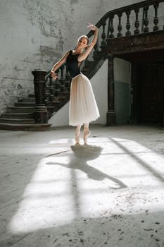 Graceful ballerina posing in a vintage room with sunlight casting shadows, showcasing elegance and skill.